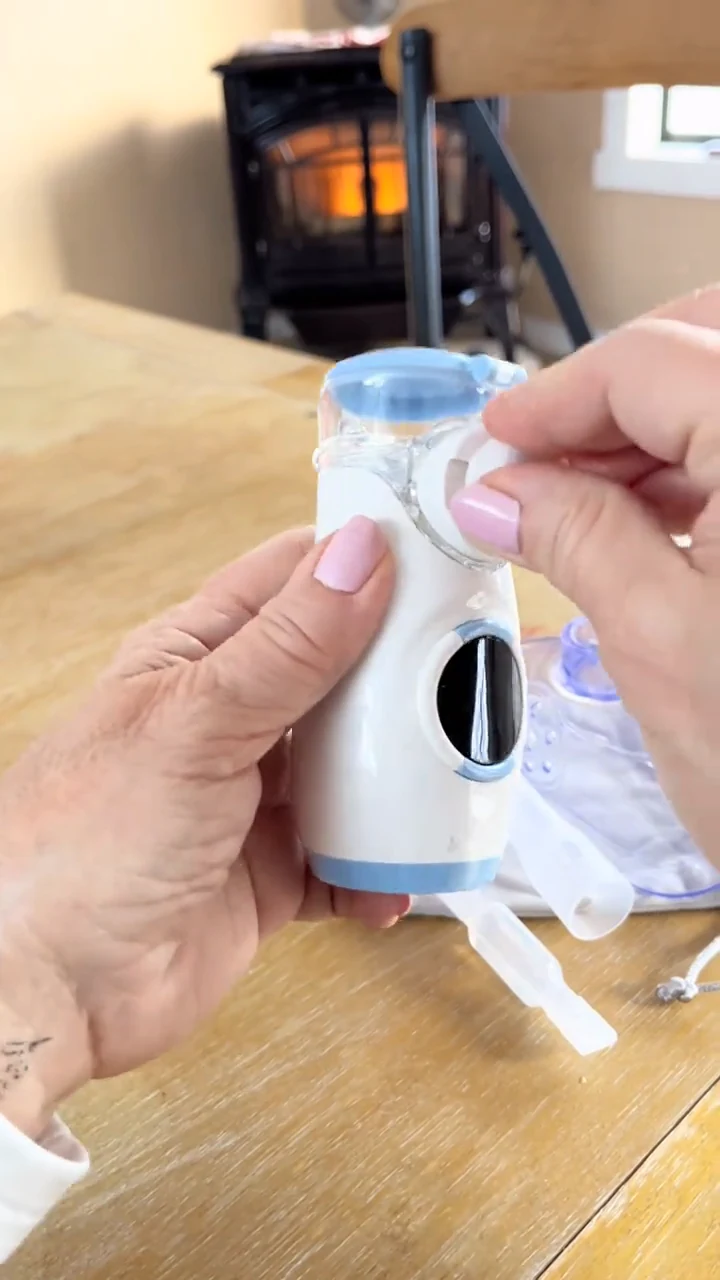 Hands holding a Mayluck handheld nebulizer at a table